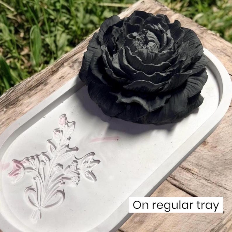 In aromatherapy passive diffuser that is shaped like a black peony flower is sitting on a cream colored embossed tray. It has just been given as a housewarming gift for a gardening friend.