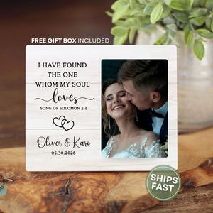 May include: A rectangular white wood-grain plaque featuring the text I HAVE FOUND THE ONE WHOM MY SOUL loves SONG OF SOLOMON 3:4, two heart outlines, the names Oliver & Kari, the date 05.30.2026, and a photograph of a couple embracing.