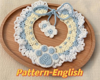 May include: A crocheted dog collar with a blue and white paw print, two white flowers, and a yellow and blue bow. The collar is on a wooden surface. Pattern-English