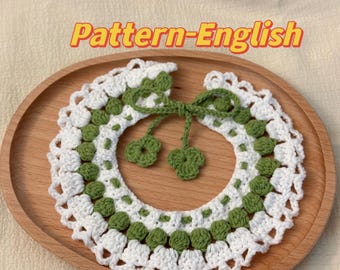 May include: A white and green crocheted collar with a bow. The collar is made with a delicate stitch pattern and features a row of green circles.