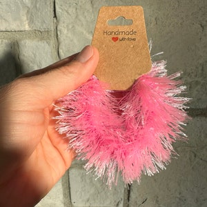 May include: Pink fluffy yarn with a brown tag that says "Handmade with love".