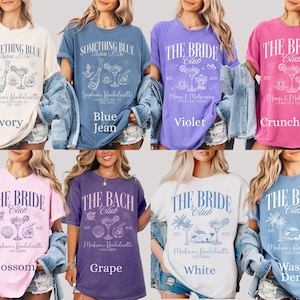 May include: A collection of eight colorful t-shirts. Each shirt features a unique design with text and graphics related to bachelorette parties. Colors include ivory, blue jean, violet, crunchberry, blossom, grape, white, and washed denim.