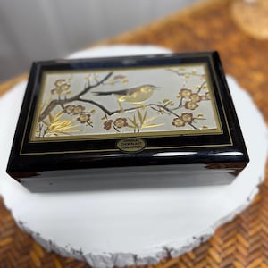 May include: Black rectangular box with a decorative lid featuring a gold and silver bird perched on a branch with gold flowers. The box has a glossy finish and the text "ORIGINAL CHOKIN ART COLLECTION".