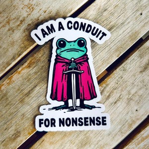Puede incluir: Una pegatina con un dibujo de una rana con una capa rosa sosteniendo una espada. La rana es verde con ojos grandes. El texto de arriba dice "I AM A CONDUIT" y debajo "FOR NONSENSE".