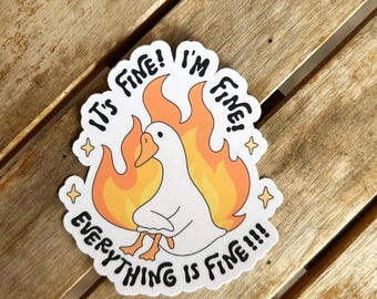 Pode incluir: Um autocolante branco com um desenho de um ganso em chamas. O texto diz "It's Fine! I'm Fine! Everything is Fine!!!". O design inclui estrelas amarelas e chamas laranja, criando uma imagem humorística.