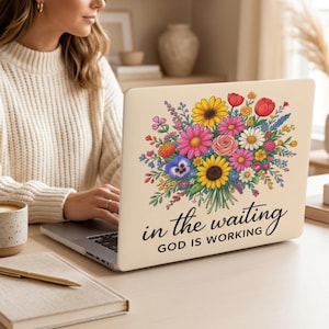 May include: A cream-colored laptop skin featuring a vibrant, multi-colored floral bouquet illustration with sunflowers, daisies, and roses. Below the flowers, the black text reads, "in the waiting GOD IS WORKING" in a mix of script and sans-serif fonts.