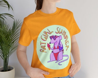 May include: A bright orange t-shirt with a graphic of a purple rat wearing sunglasses and a bikini holding an ice cream cone. The graphic is in a circle with the text "Rat Girl Summer" around it.