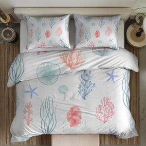 May include: A white bedding set featuring a repeating pattern of watercolour-style marine life, including pink and blue coral, light blue starfish, sea urchins, and seaweed. The set includes two rectangular pillowcases and a large duvet cover.