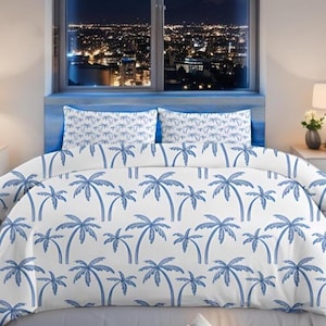 Pode incluir: Conjunto de roupa de cama branco com um padrão de palmeiras azuis. O conjunto inclui uma capa de edredão e duas fronhas. O quarto tem uma vista noturna de uma cidade através de uma janela.