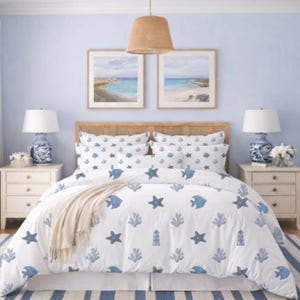 Op de afbeelding: Een slaapkamer met een nautisch thema, met een witte dekbedovertrek met blauwe vissen, zeesterren en koraalpatronen. De kamer heeft bijpassende kussens, een beige deken en een blauw-wit gestreept tapijt. Twee ingelijste strandlandschapsschilderijen hangen boven het bed.