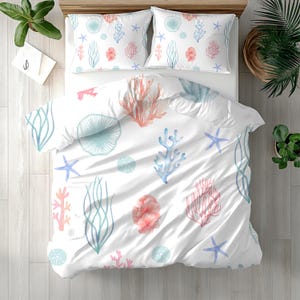 May include: A white bedding set consisting of a duvet cover and two pillowcases, featuring a repeating pattern of watercolour-style marine life including light blue starfish, pink coral branches, and pale blue sea urchins on a white background.