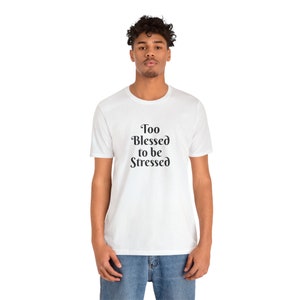 May include: White t-shirt with black text that reads "Too Blessed to be Stressed".