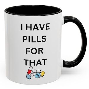 May include: White coffee mug with a black rim and handle. The mug has black text that reads "I have pills for that" and a graphic of colorful pills.