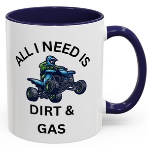 Puede incluir: Taza de cerámica blanca con interior y asa azul marino. La taza presenta el texto "ALL I NEED IS DIRT & GAS" con una ilustración de una persona montando un quad en azul y verde.