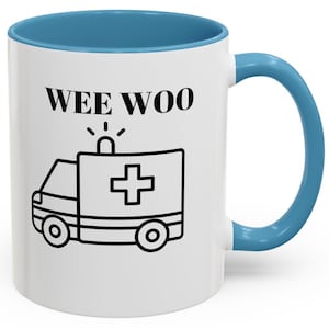 May include: White ceramic mug with a blue rim and handle. The mug has a black outline of an ambulance with a red cross and the text "WEE WOO" in black.