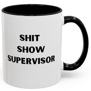 Può includere: Tazza in ceramica bianca con interno e manico neri. La tazza presenta il testo "SHIT SHOW SUPERVISOR" in grassetto nero, un regalo umoristico per un supervisore o manager.