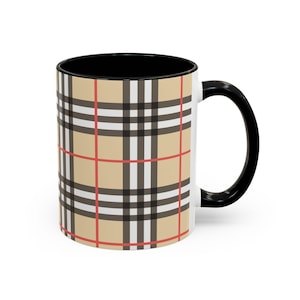 Könnte beinhalten: Eine Keramik-Kaffeetasse mit schwarzem Innenraum und Griff. Die Außenseite weist ein beige-, schwarz-, rot- und weiß kariertes Muster auf. Geeignet für heiße oder kalte Getränke.