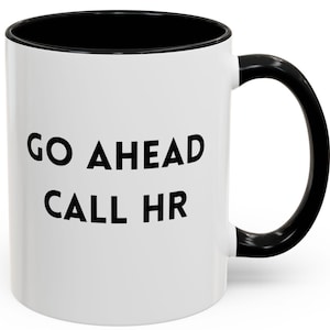Puede incluir: Taza de café de cerámica blanca con borde y asa negros. La taza tiene texto negro que dice "GO AHEAD CALL HR".