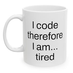 Könnte beinhalten: Weiße Keramik-Kaffeetasse mit schwarzem Text, der "Ich programmiere, also bin ich... müde" lautet.