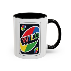 May include: White ceramic mug with a black interior and handle. The mug features a colourful graphic of a Wild card from the card game Uno. The card design includes the word "WILD" in bold letters.
