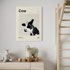 May include: A black and white cow with a beige background. The poster has the word "Cow" in black text at the top and the text "Be Abundant" and "Habitat: Grassland" in smaller black text at the bottom. The poster has a number "1/14" in the top right corner.