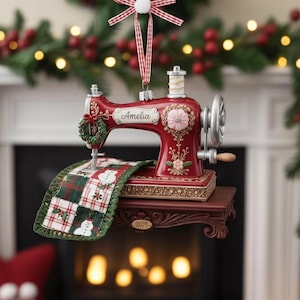 May include: A festive red and gold Christmas tree ornament in the shape of a vintage sewing machine. The ornament features the name "Amelia", a small wreath, and a miniature quilt with snowmen. The year "2025" is also displayed.