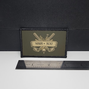 May include: Olive green rectangular patch with a black border. The patch features a golf-themed design with crossed golf clubs, a golf ball, and the text "YOUR • TEXT" in a banner. A stainless steel ruler is next to the patch.
