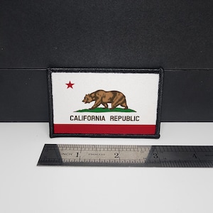 May include: Rectangular patch featuring the California Republic flag. The design includes a brown bear, a red star, and the text "CALIFORNIA REPUBLIC" on a white background with a red stripe at the bottom. The patch is bordered with black stitching.