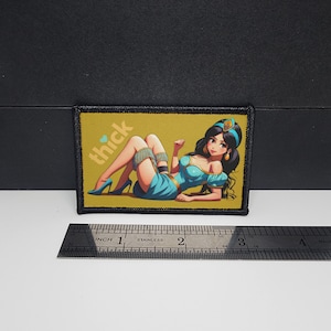 May include: A rectangular patch featuring an anime-style illustration of a woman in a teal outfit, high heels, and jewelry, with the word "thick" in the upper left corner. The patch has a black border and is set against a yellow background.