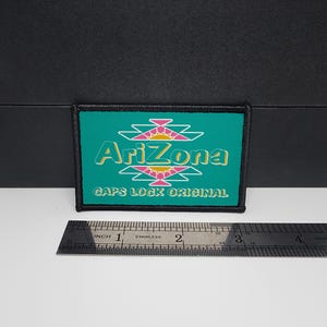 May include: Rectangular patch with the word "Arizona" in teal and white, with a pink and yellow design above and below the text. The text "GAPS LOCK ORIGINAL" is below the word "Arizona". The patch is approximately 3 inches wide.