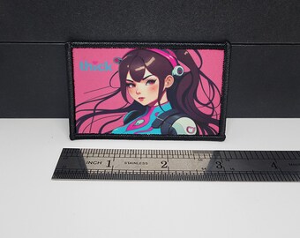 May include: A rectangular patch featuring a colorful anime-style illustration of a woman with long dark hair, wearing a headset and a blue and pink outfit. The word "thick" is printed in light blue. The patch is approximately 3 inches wide.