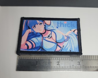 May include: Rectangular patch with a colorful anime-style illustration of a woman with blue hair and a light blue outfit. The word "thick" is printed on the patch. The patch is bordered with black stitching and measures approximately 3 inches wide.