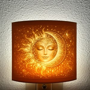 May include: A decorative night light with a celestial design. The lamp shade features a detailed illustration of a sun and moon with a face, set against a starry background. The color palette is warm, with shades of orange and gold.