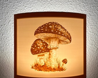 May include: A nightlight with a white ceramic shade featuring a detailed illustration of three mushrooms with brown caps and white stems. The mushrooms are surrounded by green grass and leaves.