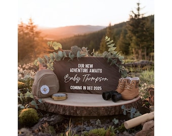 Può includere: Un cartello di legno con il testo "Our new adventure awaits Baby Thompson coming in Dec 2025". Uno zainetto marrone piccolo con un design a bussola, una bussola e un paio di scarponi da trekking marroni sono disposti su una superficie di legno davanti al cartello.