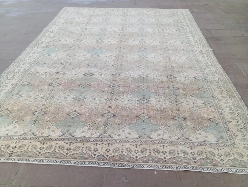 May include: Large rectangular area rug with a faded, vintage appearance. The rug features a central pattern of muted blues, pinks, and tans, framed by a detailed border. The overall design suggests a traditional, oriental style.