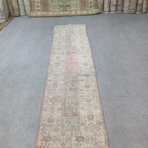 May include: A long, narrow, cream-colored rug with a pink and green floral pattern. The rug has a fringe border.