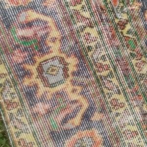 May include: Close-up of a colourful rug with intricate patterns in shades of red, orange, yellow, green, and blue. The rug has a woven texture and a fringed edge.