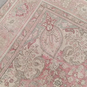 May include: A woven rug featuring a faded palette of dusty rose, muted sage green, and cream. The surface displays an intricate pattern of stylised floral motifs, paisley shapes, and geometric borders with a distressed, weathered texture.