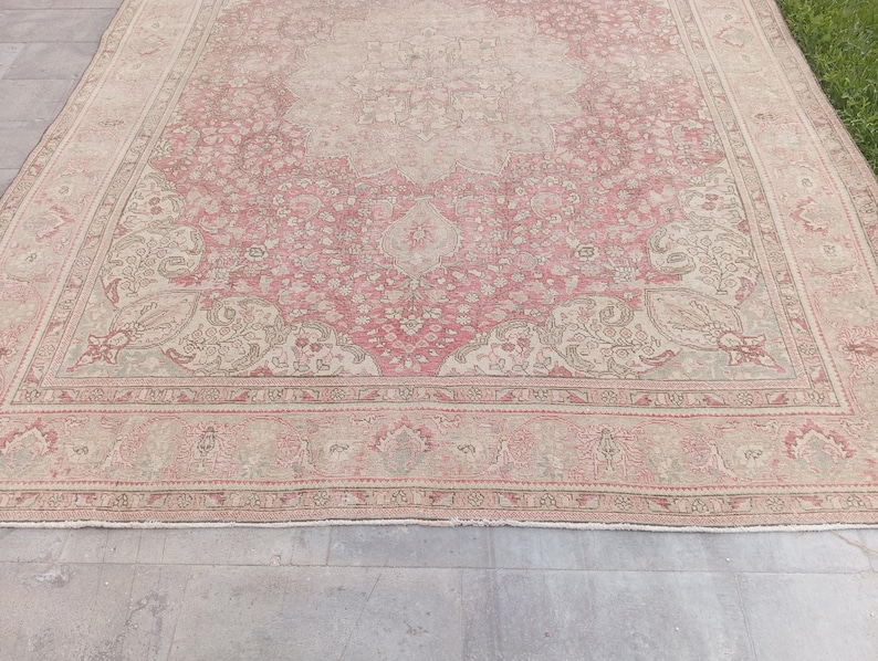 May include: A large rectangular area rug featuring a central medallion design in shades of dusty rose and beige. The rug displays an intricate floral pattern throughout the field and a wide decorative border with repeating botanical motifs.