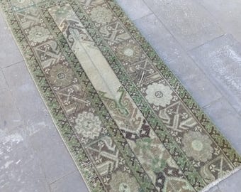 Puede incluir: Una alfombra de pasillo vintage verde y marrón con un patrón geométrico. La alfombra tiene un borde con flecos y está hecha de lana.
