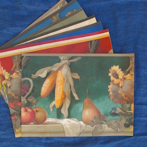 May include: A collection of art prints featuring still life compositions with autumnal themes. The prints showcase images of corn, apples, pears, and sunflowers. The color palette includes shades of yellow, orange, green, and red.