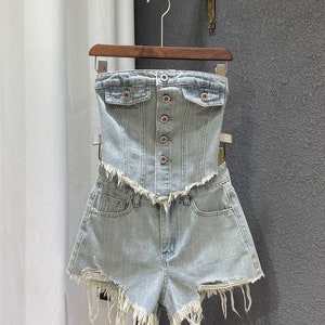 Puede incluir: Un top corto de mezclilla azul claro con cierre de botones y un par de pantalones cortos de mezclilla a juego con bordes deshilachados.