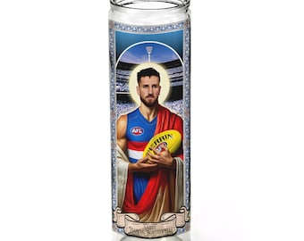 May include: A glass candle with a colorful image of a man holding a football. The image is framed with a gold border and includes the text "SAINT HARRIS ANDREWS".