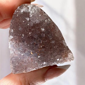 May include: A purple amethyst crystal cluster with a rough, natural texture. The crystal has a light purple hue and is translucent.