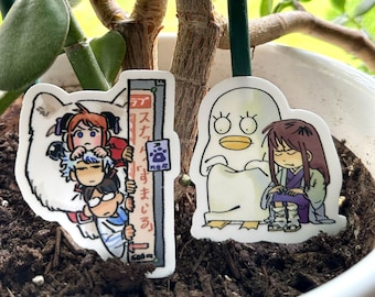 May include: Two die-cut stickers featuring characters from the anime Gintama. One sticker shows a group of characters, and the other depicts a character with a duck-like creature. The text "gintama die-cut stickers" is at the bottom.