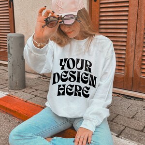 White gildan 18000 mockup white sweatshirt mockup Oversized blank white sweatshirt gildan g180 model mockup, Trendy outdoors lifestyle mock image 1