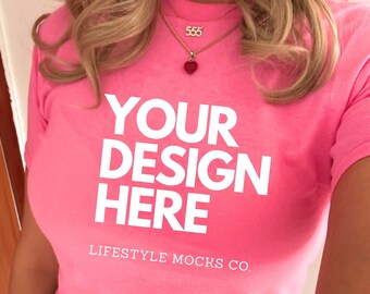 May include: A pink cropped t-shirt with the text "YOUR DESIGN HERE" and "LIFESTYLE MOCKS CO." printed on the front. The shirt is being worn by a person with blonde hair and a necklace.