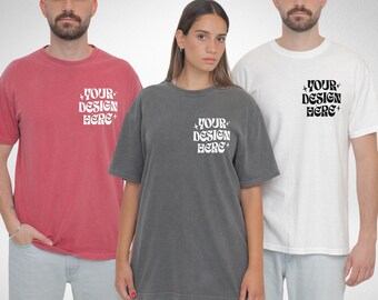 May include: Three people wearing different colored t-shirts with the text "YOUR DESIGN HERE" printed on the front. The shirts are a red, gray, and white.