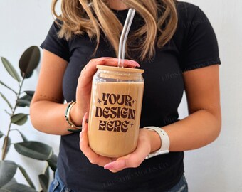 May include: A person holding a clear glass tumbler with a bamboo lid and a straw. The tumbler is filled with a light brown liquid and has the text "YOUR DESIGN HERE" printed on the side.